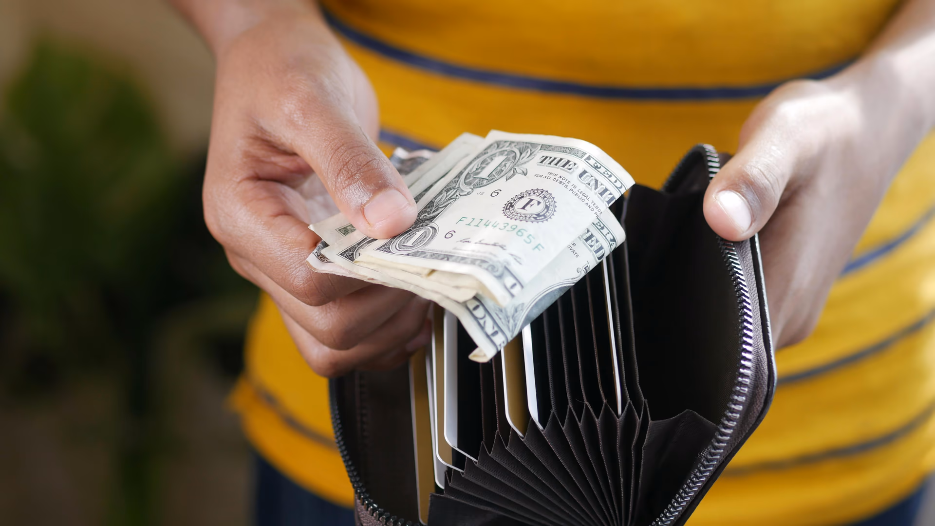 Close-up of a person's hands holding US dollar bills and a wallet - Image by Towfiqu barbhuiya from Pexels