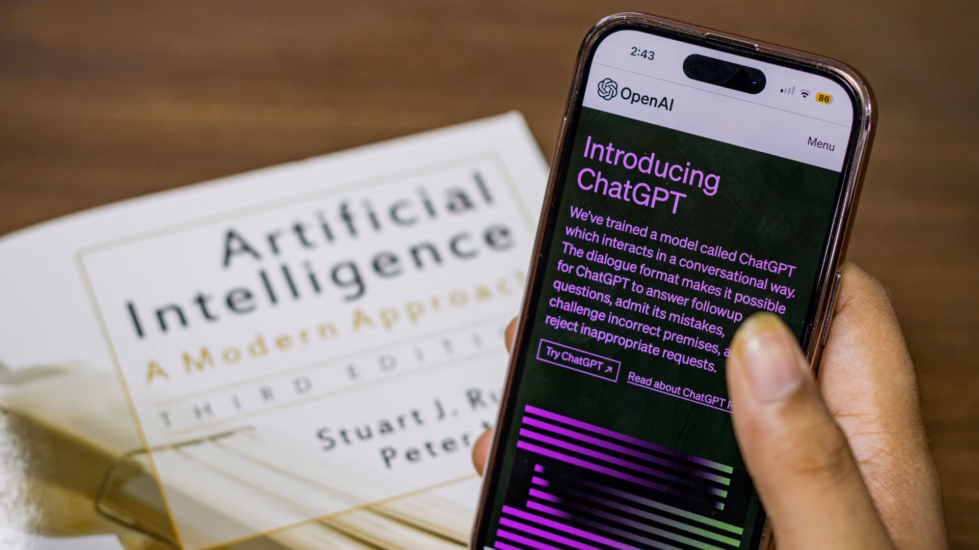 Close-up of a smartphone displaying ChatGPT app held over AI textbook - Image by Sanket Mishra from Pexels