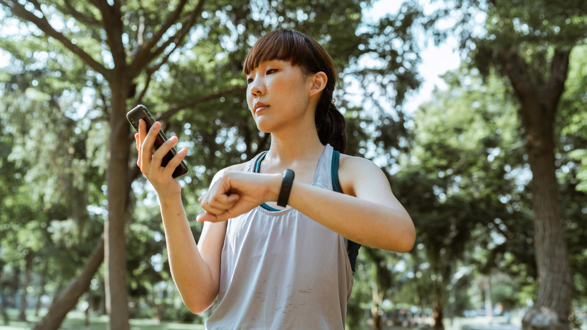 Young woman checking her fitness tracker on a sunny day in the park, staying active and healthy - Image by Ketut Subiyanto from Pexels