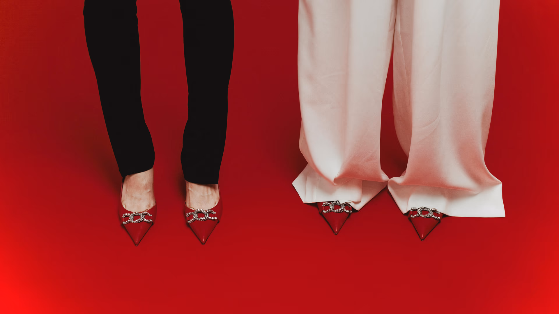 Elegant red shoes with crystal designs paired with black and white pants on red surface - Image by SHVETS production from Pexels