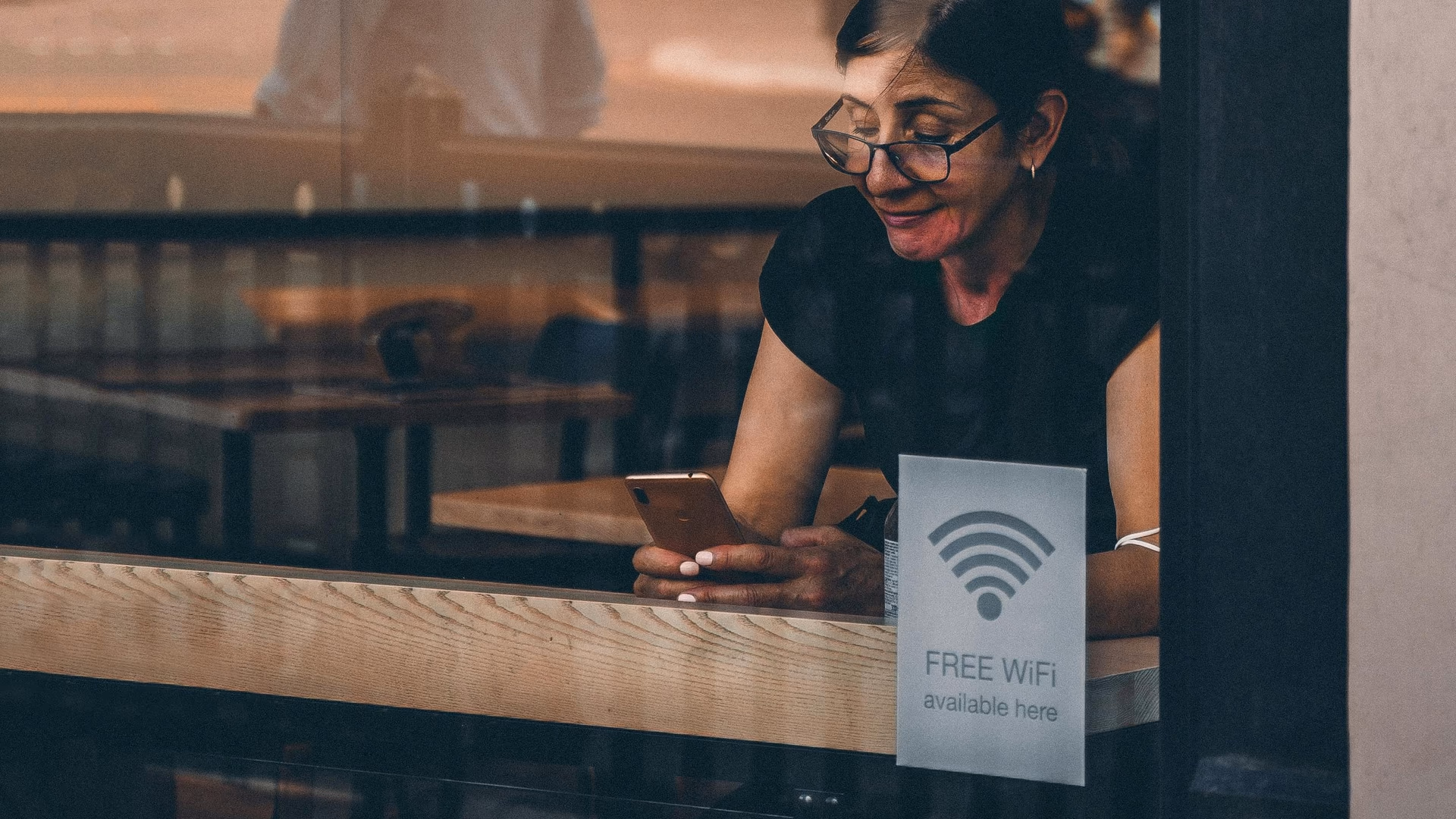 A woman using her smartphone at a cafe window in London, reflecting urban lifestyle - Image by Andrea De Santis from Pexels