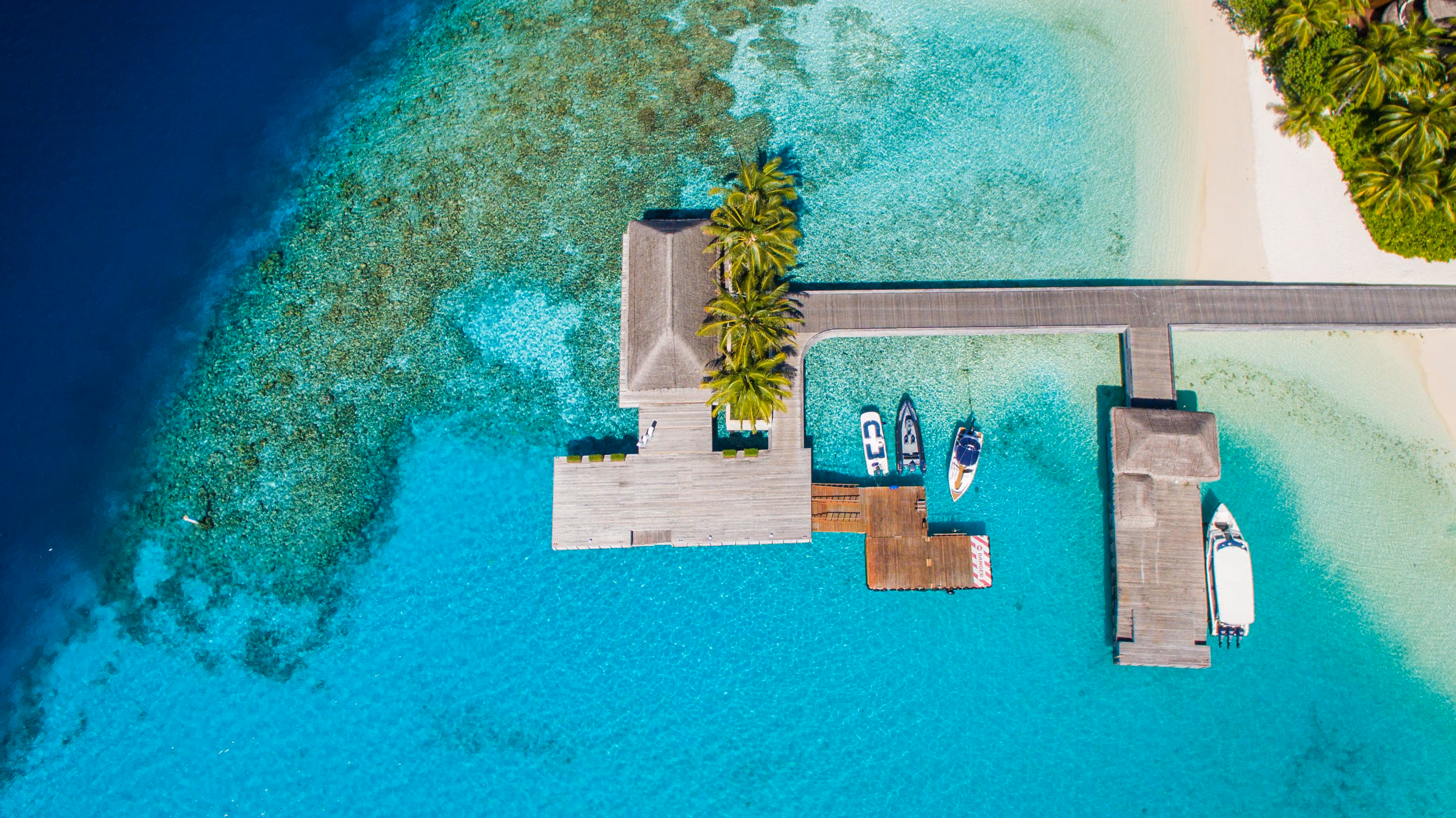 Stunning aerial view of a dock with boats on crystal-clear turquoise waters in the Maldives -Image by Firushan Numaam from Pexels